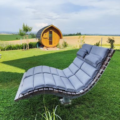 Gemütliche Himmelsliege mit Auflage vor einer Gartensauna